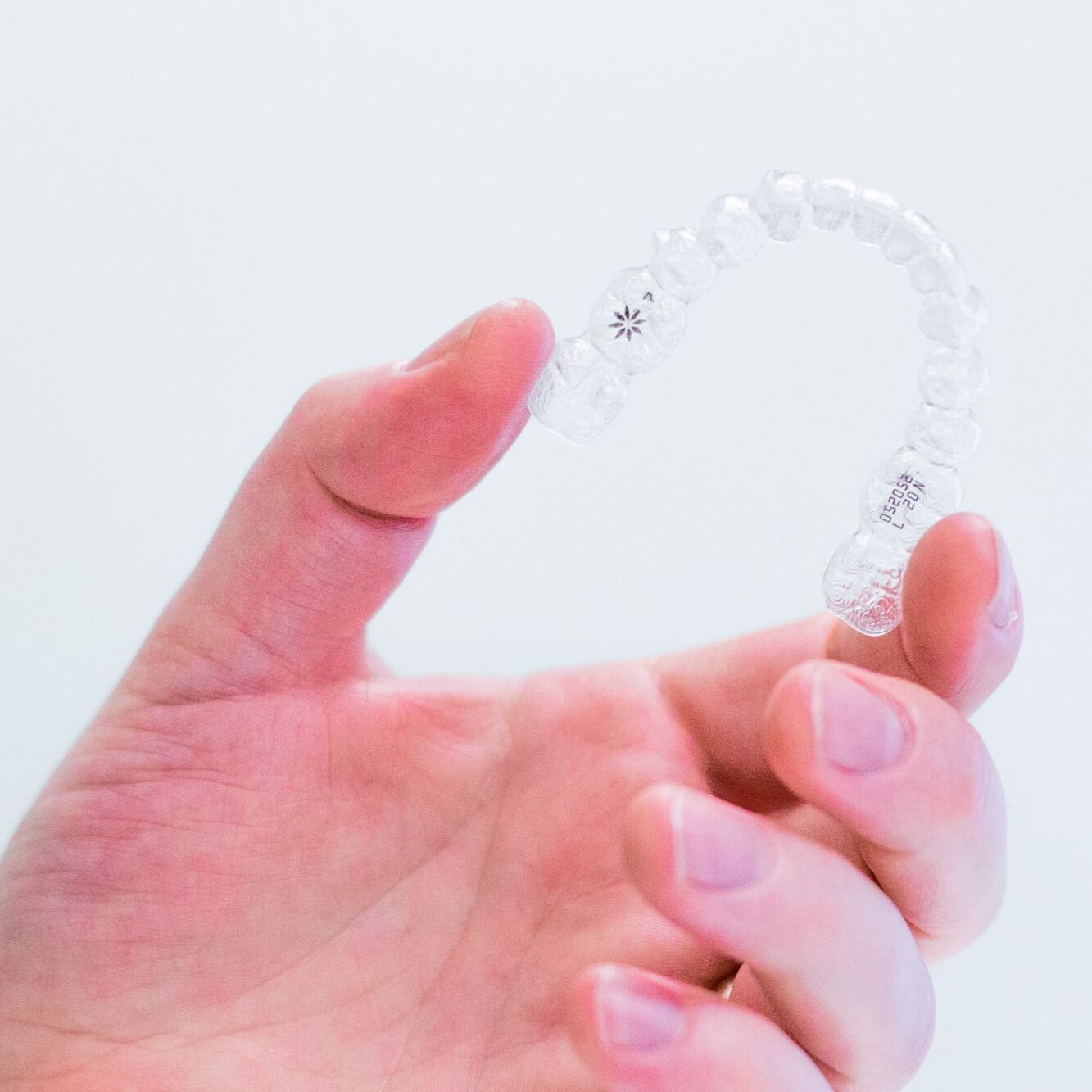 Clear Aligners from an Orthodontist in Stephenville Hand holding clear aligners provided by an orthodontist in Stephenville